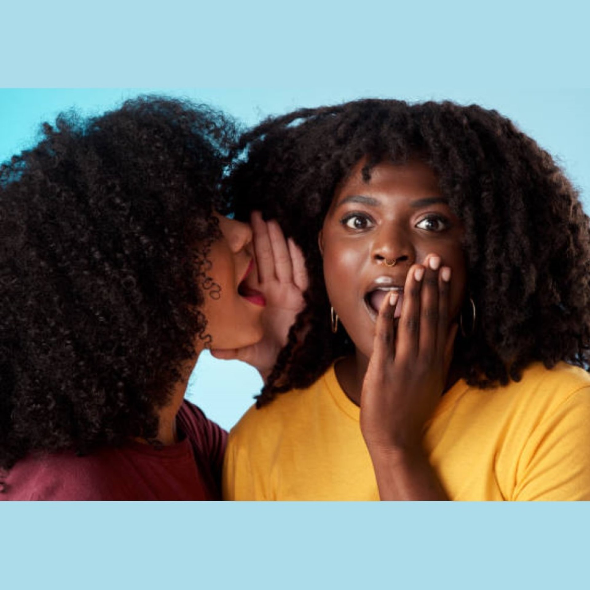 2 black women gossiping. woman whispering in shocked friend's ear. turquoise background.